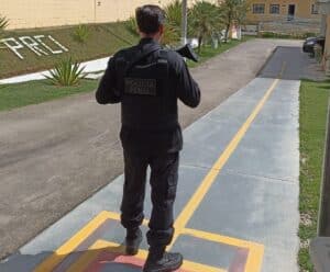 Policial penal, de costas, segurança uma arma enquanto faz a segurança na penitenciária
