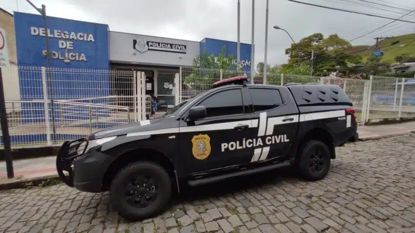 ´Carro preto caracterizado com logo da Polícia Civil em frente a uma Delegacia