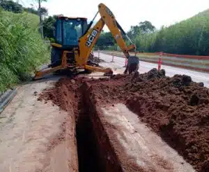 BRK moderniza serviços em mais 12 bairros e localidades de Cachoeiro Uma escavadeiraesta na lateral de uma rua, e cava um buraco.