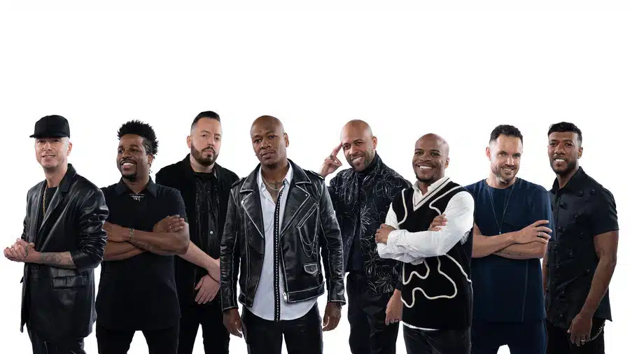 Todos os oito integrantes do grupo Turma do Pagode estão lado a lado posando para a foto.