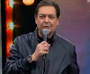 Band oficializa a saída de Faustão e revela quem vai dirigir novo programa apresentador Faustão com blusa de frio preta e microfone