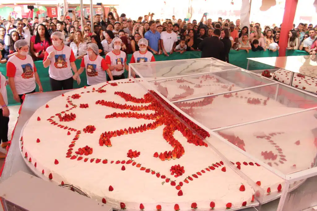 pessoas em volta de torta gigante de morango