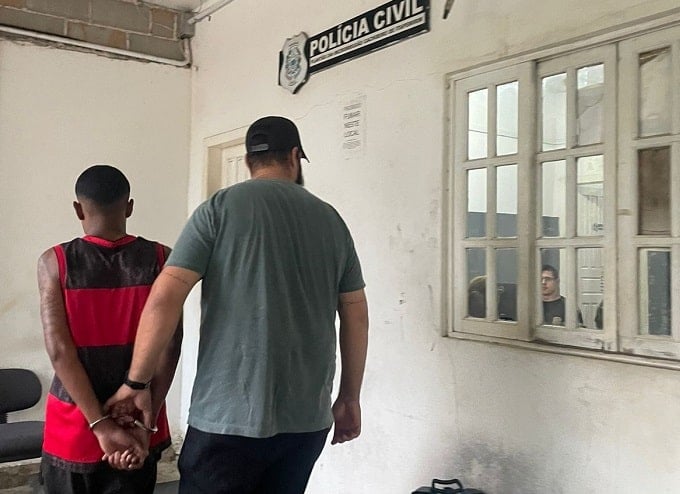 Homem usando camisa do flamengo sendo preso por policial civil entrando na delegacia de Cachoeiro