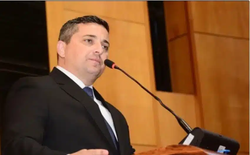 Homem de terno e gravata falando ao microfone