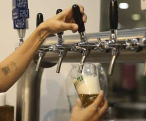 Mão feminina retirando cerveja de uma máquina