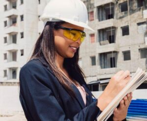 Sine começa última semana de maio com 972 vagas de emprego Mulher com capacete na cabeça, escrevendo em uma prancheta, em um canteiro de obras