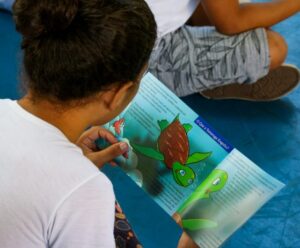 Anchieta elege novos conselheiros tutelar neste domingo (1º) criança de costas com um livro ilustrado em mãos