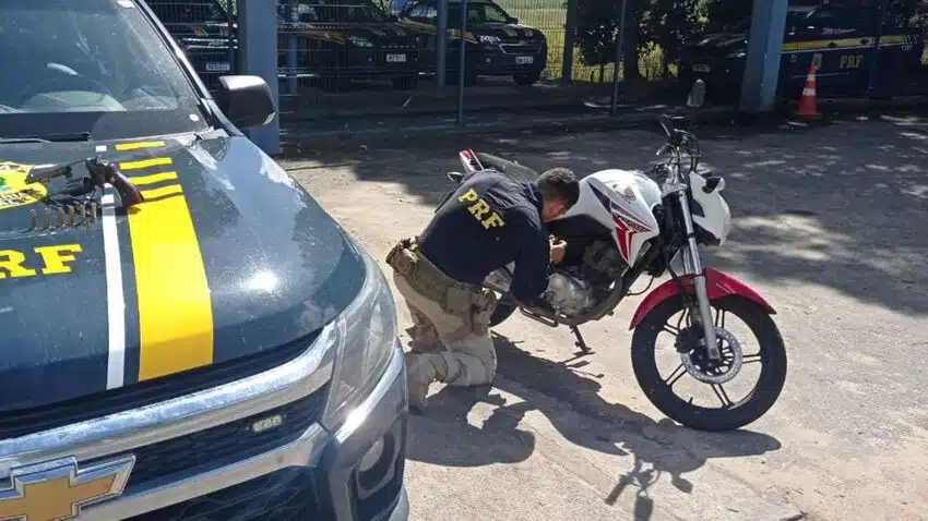 carro da PRF ao lado de moto e policial verificando