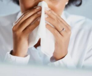 mulher com roupa branca assoando o nariz com lenço branco