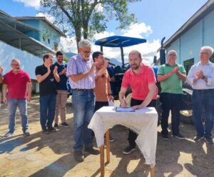 Na imagem várias pessoas da Prefeitura de Anchieta estão assinando a papelada de transferência do trator para a escola.