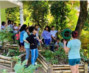 Professora ensinando aos alunos em uma área arborizada e verde