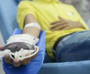 Pessoa segurando bolsa de sangue enquanto doa sangue