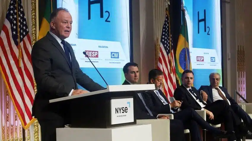 Governador faz um discursso em frente a púbito com bandeiras dos EUA ao fundo