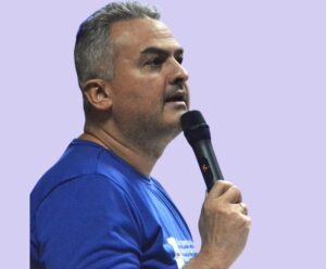 Neto Barros: “inovação para todos porque inteligência não escolhe berço” Foto de Neto Barros falando no microfone que inovação deve ser para todos porque inteligência não tem berço