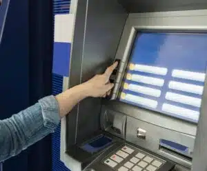 Evite golpes: Procon alerta sobre descontos indevidos em contas bancárias mãos na tela do caixa eletrônico