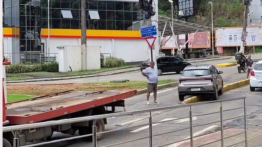 Homem parado no meio da pista em carro preso em mureta do trânsito