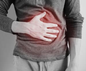 Gastroenterite: a doença pode atrapalhar as férias? Veja como fugir dela Um homem segurando a barriga como se estivesse doendo