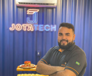 Energia Solar: 5 benefícios incríveis para residências e comércios O especialista em energia solar João Paulo da JOTATECH, loja de Cachoeiro de Itapemirim, em sua nova loja em frnete a uma parede azul