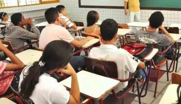 alunos sentados em cadeiras de escola estudando - Projeto Nossa História Nossa Gente