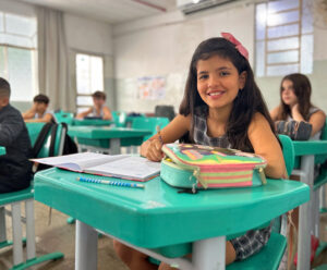 De volta para casa! Ciac abre matrículas para 2025 com foco em sua essência Aluna do 4º ano do Ciac, sentada em mesa azul, com materiais escolares