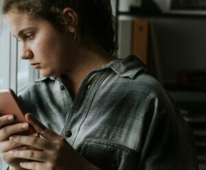O impacto das redes sociais na saúde mental dos adolescentes A foto mostra adolescente com celular