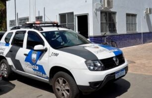 A imagem mostra uma viatura da Polícia Militar estacionada em frente a um prédio com fachada branca e azulejos azuis na parte inferior. O veículo, um Renault Duster, pertence ao 6º Batalhão da Polícia Militar (6º BPM) e possui o emblema da corporação e a identificação "Patrulha" nas portas. O ambiente indica que pode se tratar de uma unidade policial ou administrativa, localizada possivelmente em Vitória, no Espírito Santo.