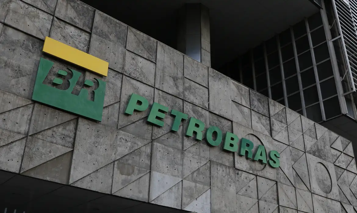 Fachada da sede da Petrobras com logotipo da empresa em destaque, representando ações PETR4 em valorização no mercado financeiro.