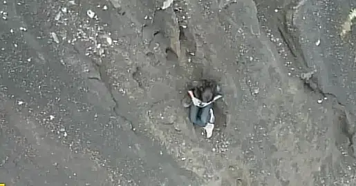 Mulher brasileira identificada como Juliana Marins é localizada caída em encosta de penhasco no vulcão Rinjani, na Indonésia, durante operação de resgate. Cena mostra o local de difícil acesso onde ela permaneceu por dois dias.