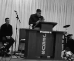 Pastor Sérgio morreu após ajoelhar em culto Pastor prega em púlpito com a palavra "Jesus" escrita em destaque, enquanto outros membros estão sentados e instrumentos musicais estão ao fundo, em igreja com cortina branca ao fundo.