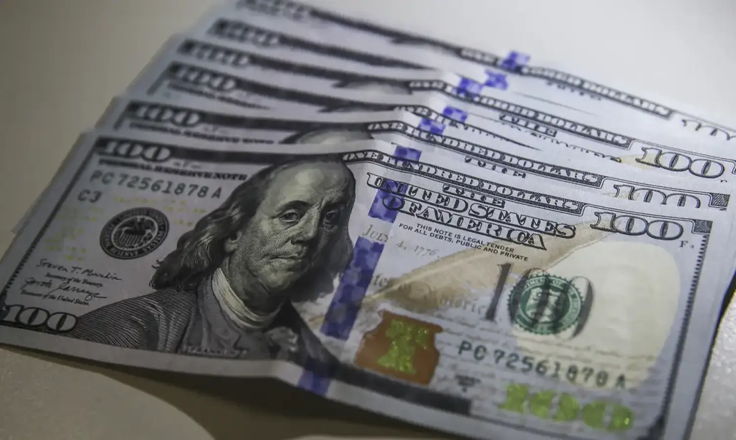 Notas de 100 dólares alinhadas, destacando a imagem de Benjamin Franklin, representando a alta na cotação do dólar hoje frente ao real.