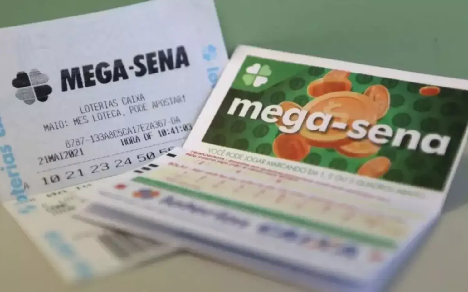 Bilhetes da Mega-Sena com números apostados e volante oficial das Loterias Caixa, ilustrando apostas para o sorteio e resultados da Mega-Sena.