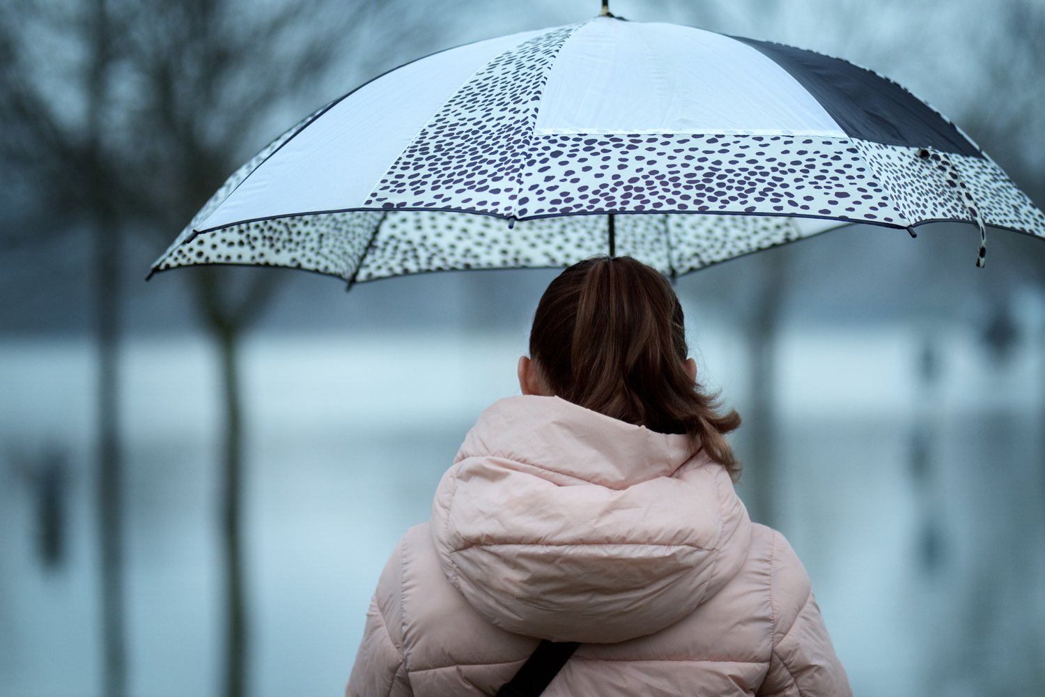 Uma mulher com sombrinha e roupa de frio aguardando a frente fria no Espírito Santo
