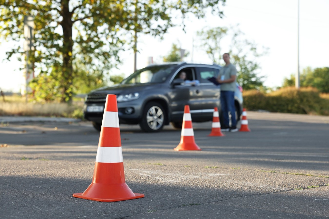 Instrutor orienta aluno durante aula prática de direção em autoescola, com cones de trânsito na pista — treinamento para exame de CNH no Espírito Santo.