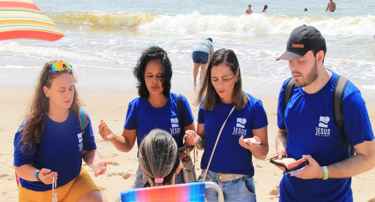 Jovens do projeto Jesus no Litoral 2026 rezam na praia durante ação missionária em Itapemirim.