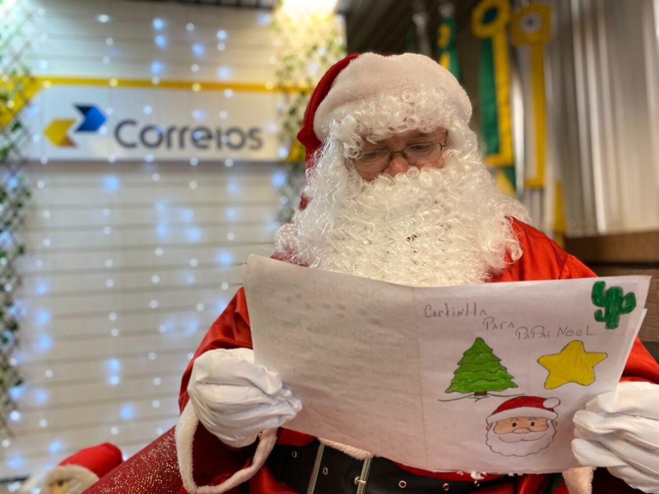 Papai noel lendo umas das cartas da Campanha Adote uma Carta de Natal dos Correios