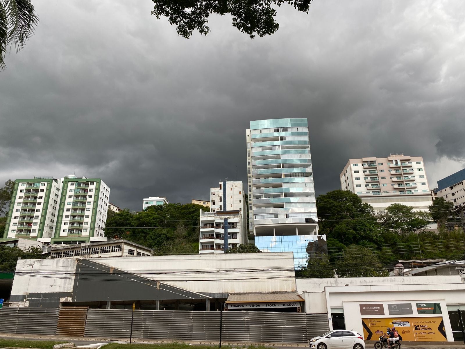 Imagem retrata paisagem com céu com nuvens carregadas para temporal em cidade