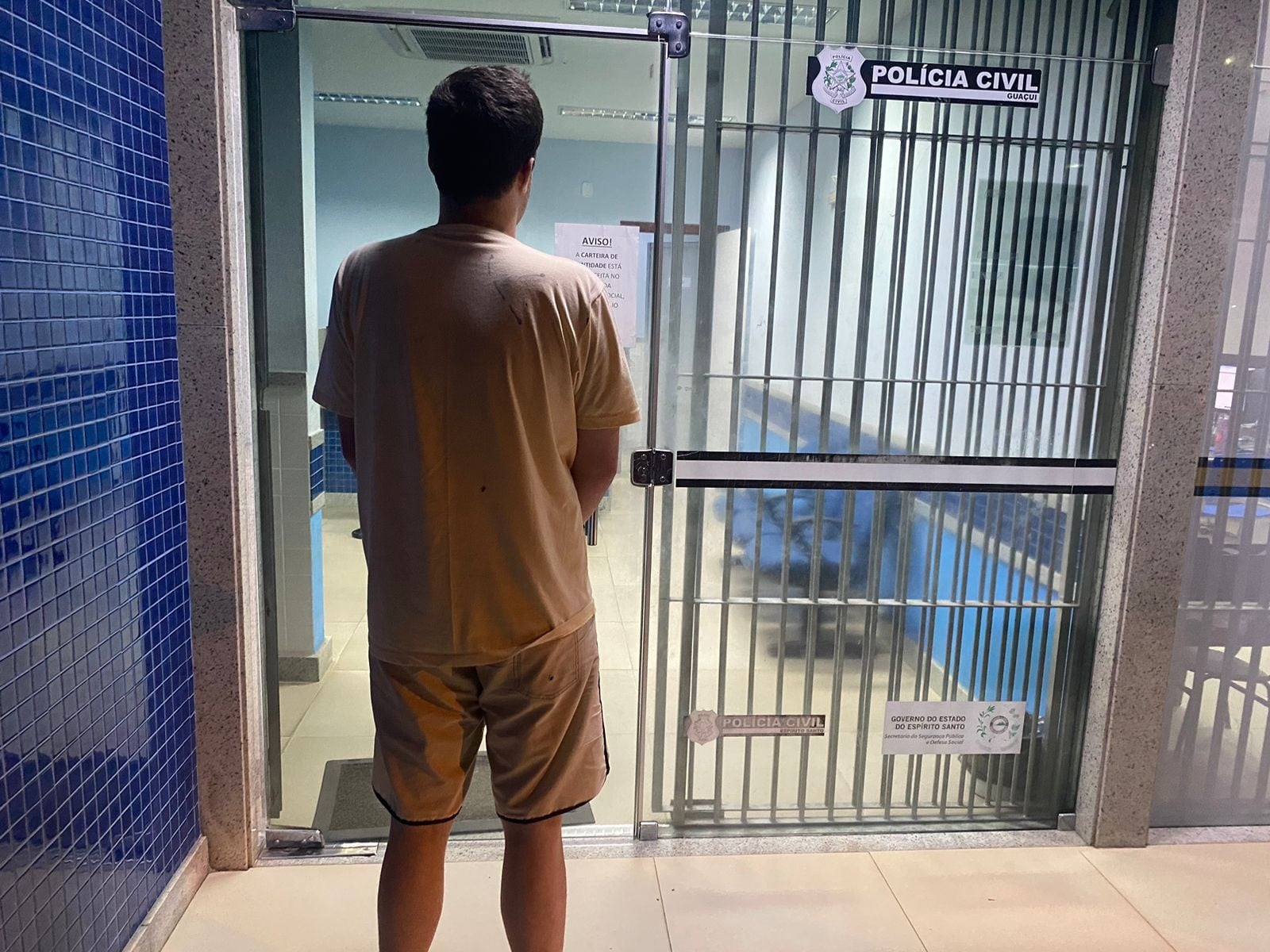 Homem de costas na frente da delegacia após ser preso por tráfico.