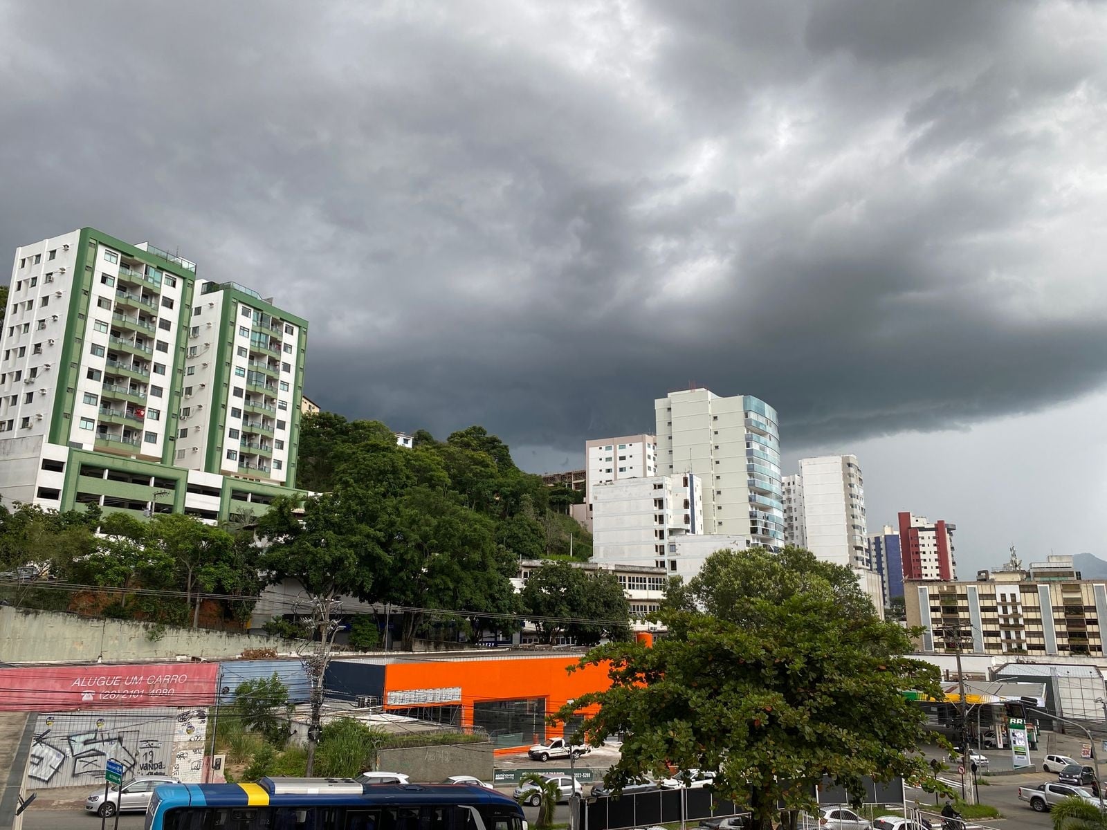 Imagem retrata céu fechado, indicando chuva forte, com prédios ao fundo.