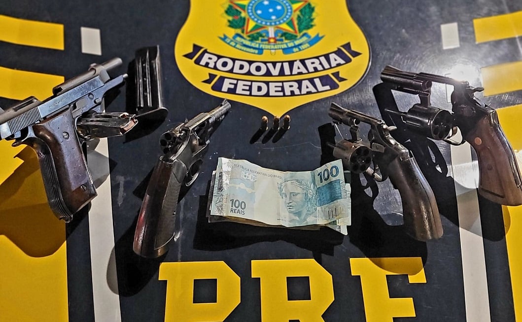 Imagem retrata quatro armar sobre o capô da viatura da PRF após apreensão.