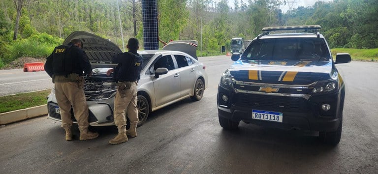 Imagem mostra carro clonado apreendido ao lado de uma viatura da PRF