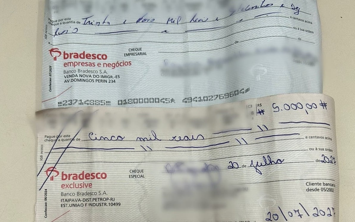 Imagem mostra folhas de cheques assinadas em uma mesa.