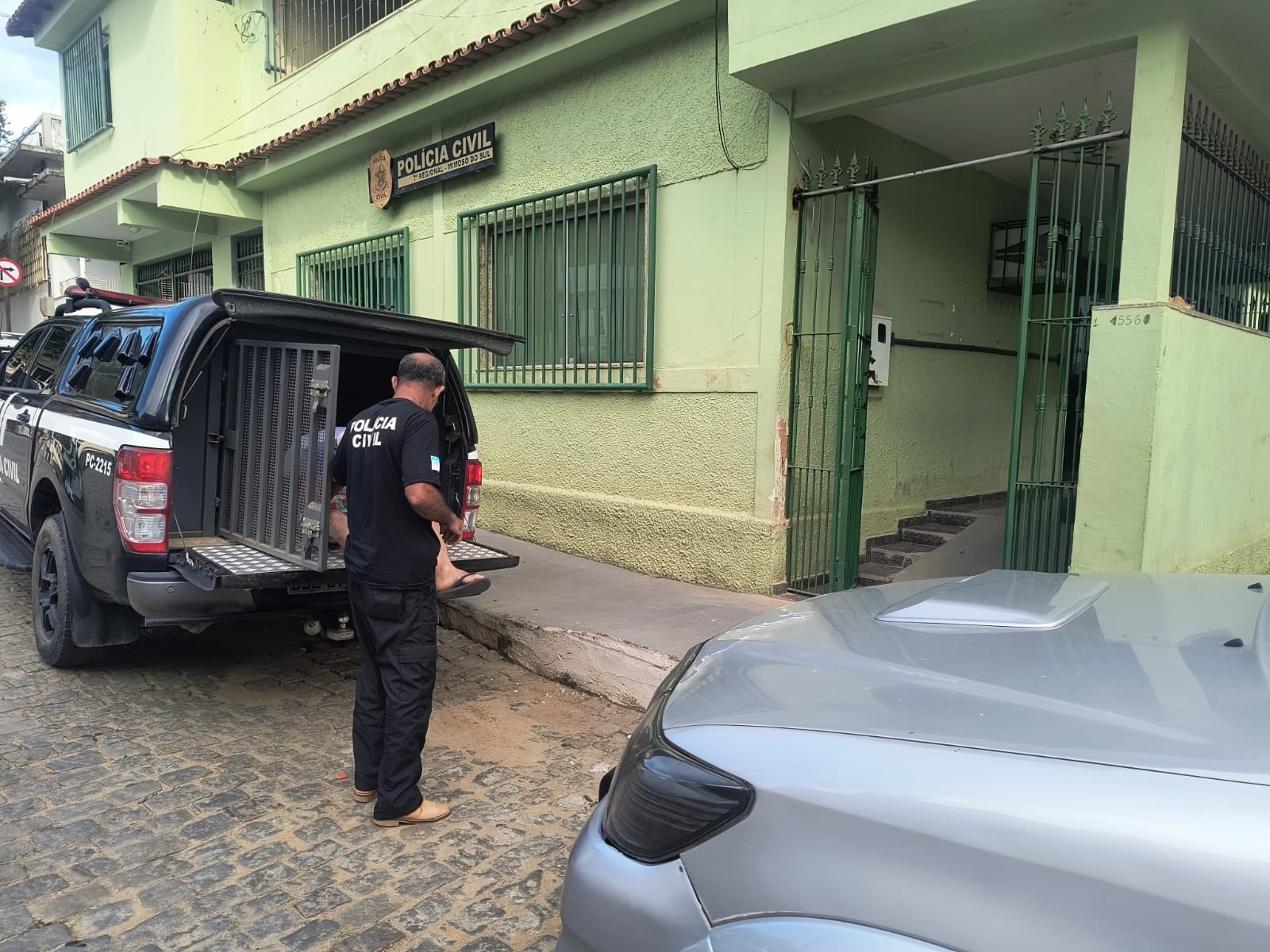 Imagem retrata policial retirando homem suspeito de estupro de viatura.