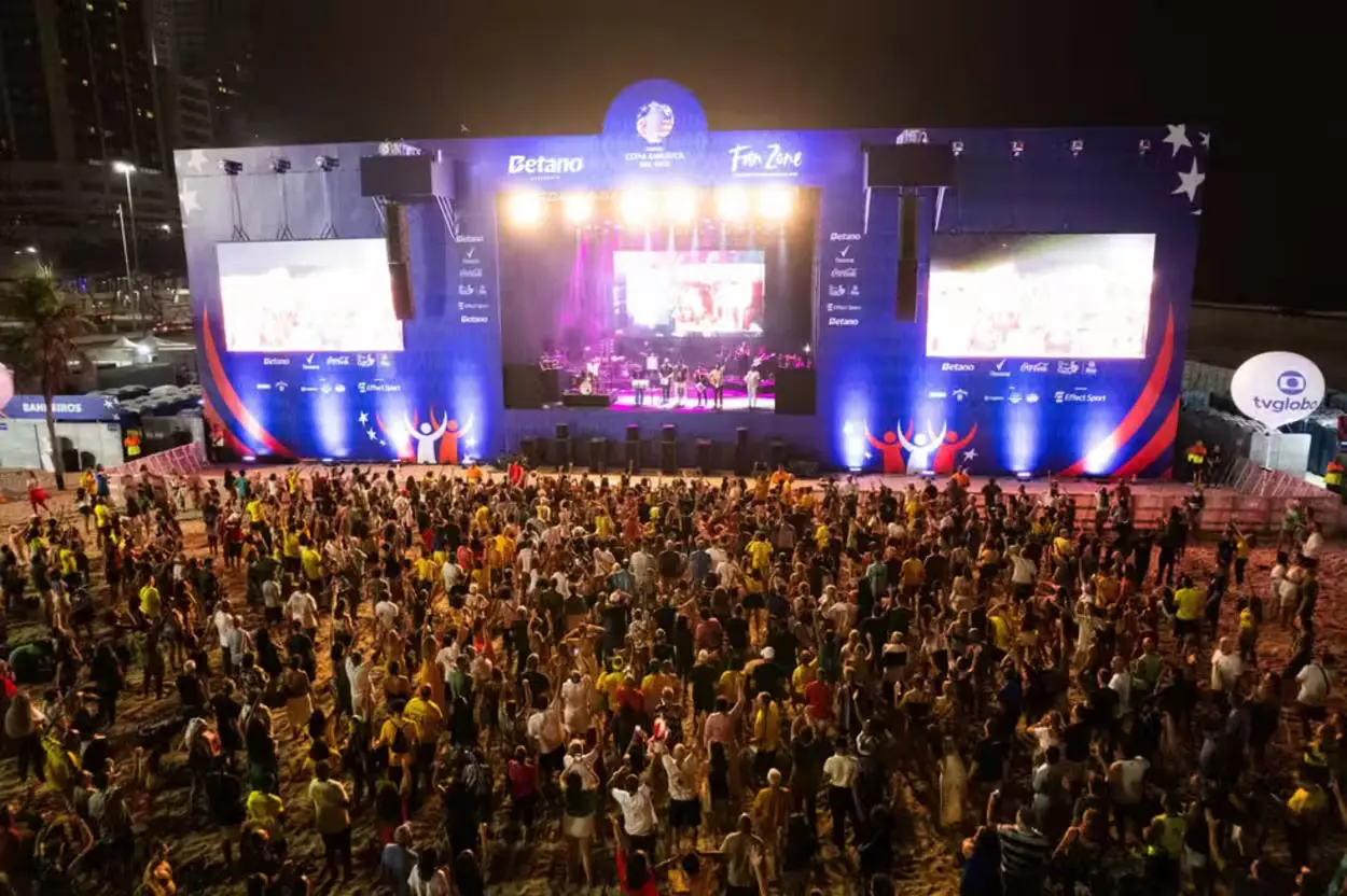 Imagem ilustra torcedores em um ambiente aberto assistindo a transmissão da partida Flamengo x PSG