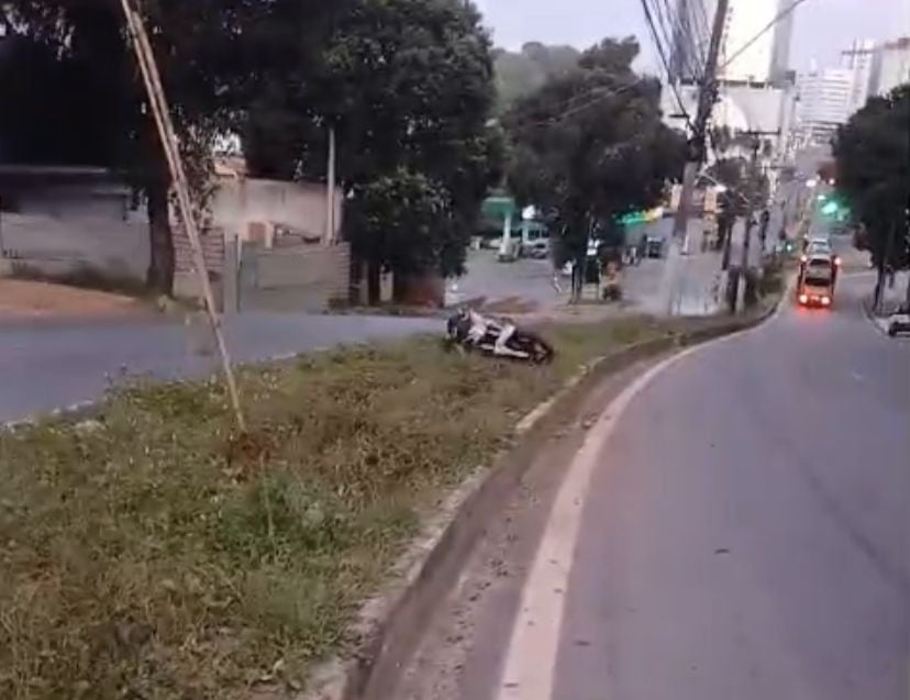 Imagem mostra rodovia com moto caída no canteiro após acidente grave.