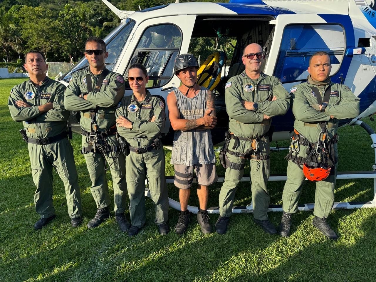 Equipe do Notaer posa ao lado do parapentista resgatado em frente ao helicóptero Harpia 02, após operação no Morro do Moxuara, em Cariacica.